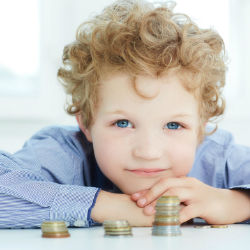 Little boy seated at table with coin stacks in front of him