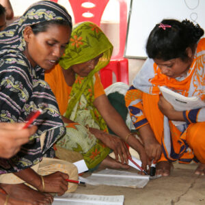 Three Bangladeshi women study workbooks in a classroom