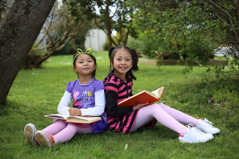 two girls sitting on grass