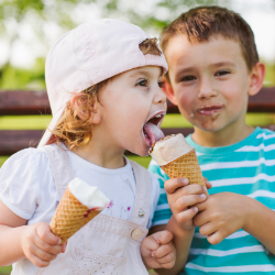 A preschool-aged boy shares his ice cream cone with a preschool-aged girl