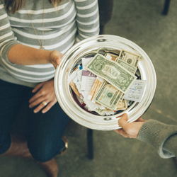 Shows a woman passing a collection plate filled with money back to a man in church.