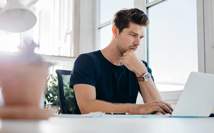 Young Man on Laptop with Coffee in Foreground