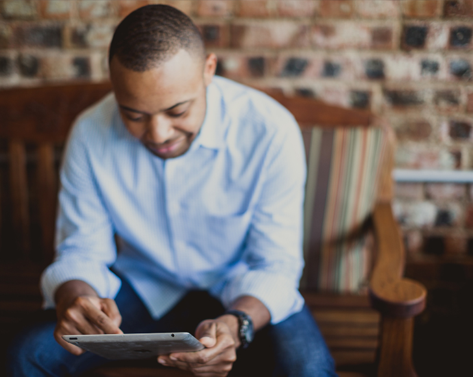 Man Sitting on Bench Looking at Tablet